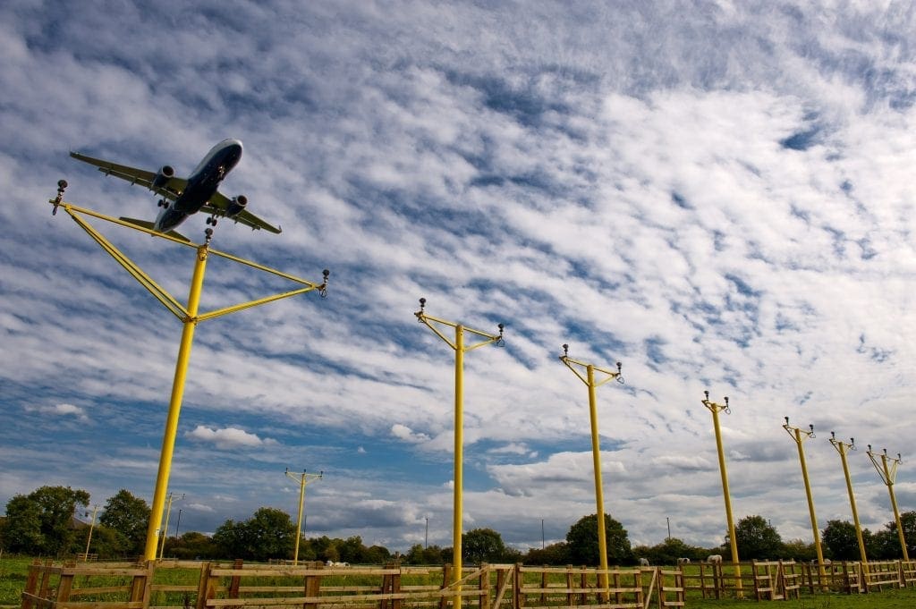 Pollite Approach Masts at an airfield with a plane flying over them - enhancing airport operations by increasing safety