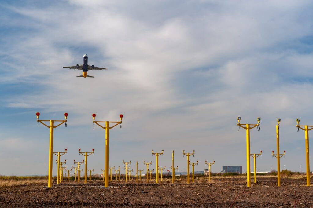 Airplane flying over field of frangible multi light monopole approach masts at Liverpool airport improving the safety and security of the airfield